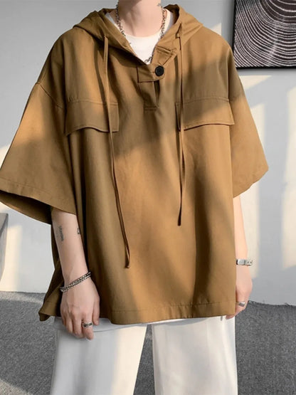 A man wearing a loose-fit black hooded short sleeve t-shirt for summer.