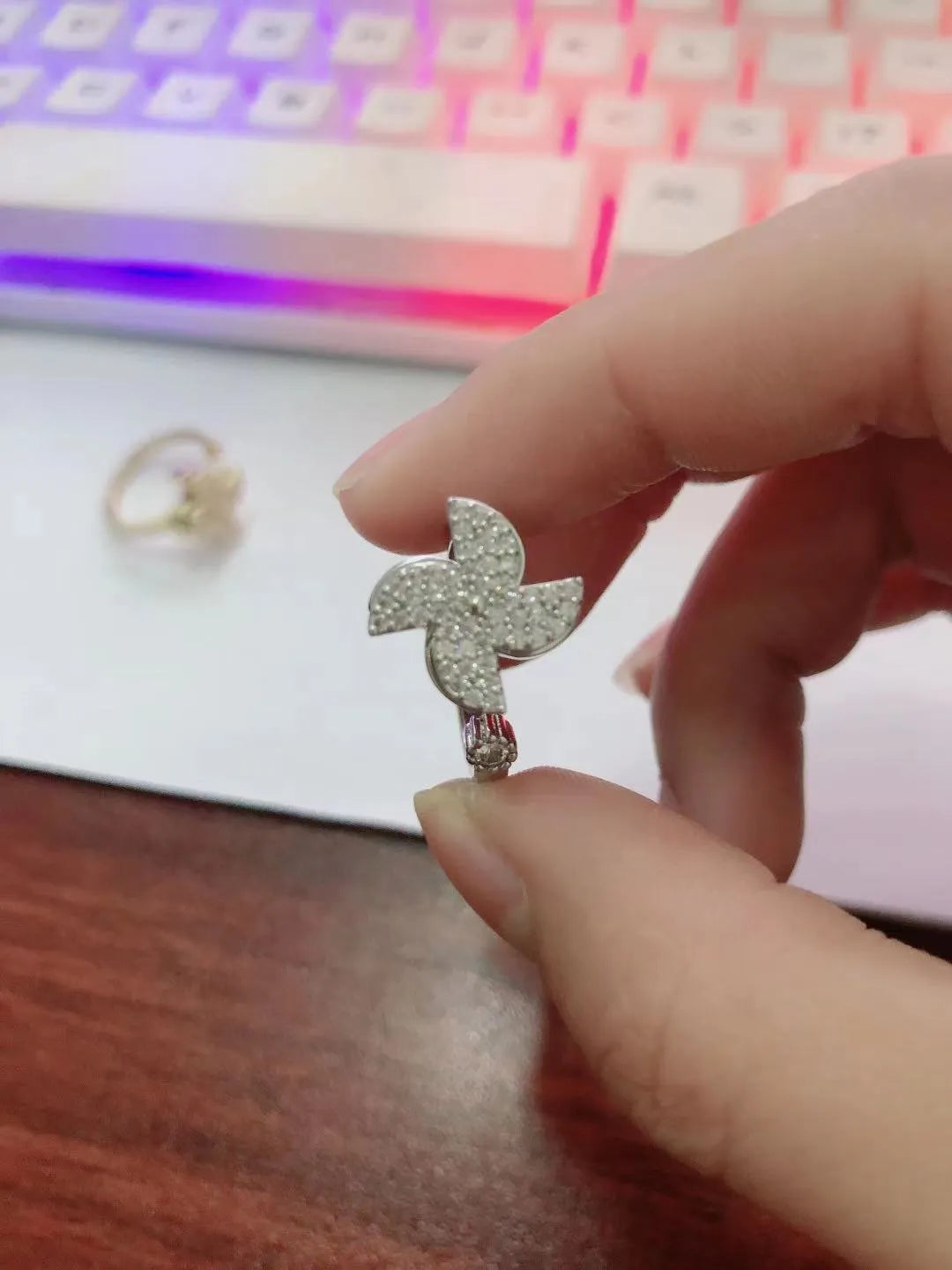 Gold-toned geometric ring with a central spinning windmill detail on a person's finger.