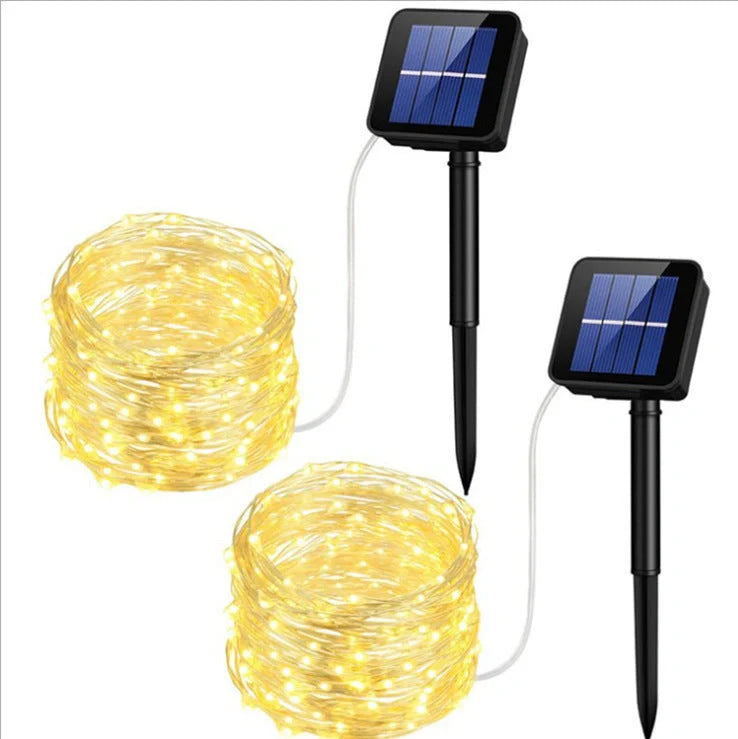 Solar-powered LED string lights arranged in garden with solar panel charging in sunlight