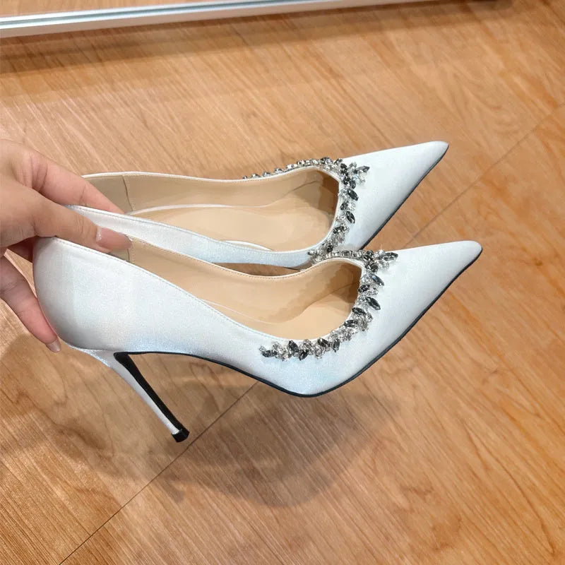 Women's black satin stiletto high heels with pointed toe and rhinestone decoration.