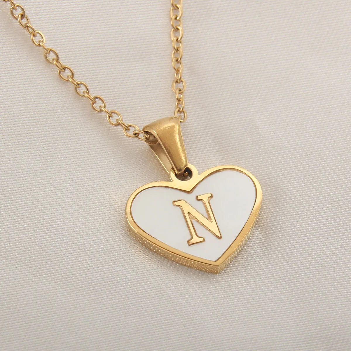 Gold-plated clavicle necklace with a white shell heart pendant, personalised with a letter from A to Z.