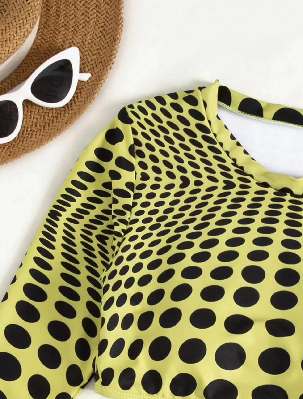 Green polka dot women's three-piece swimsuit set with top, skirt, and bra on hanger