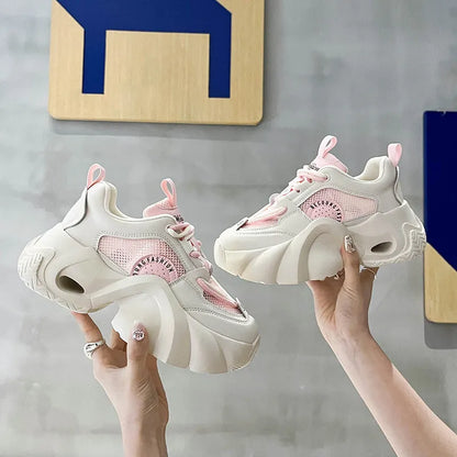 Women's pink sneakers with cross straps, thick sole, and mesh lining on a white background