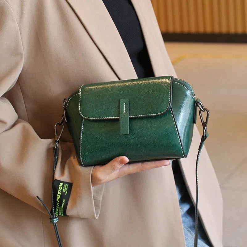 Women's brown shell-shaped genuine leather messenger bag with a single shoulder strap and visible stitching.