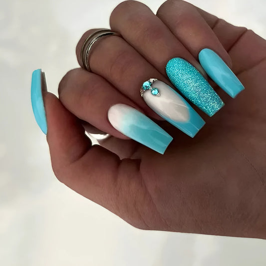 Set of 24 long ballet-shaped false nails in smart blue diamond colour with a bottle of nail glue on a pink background.