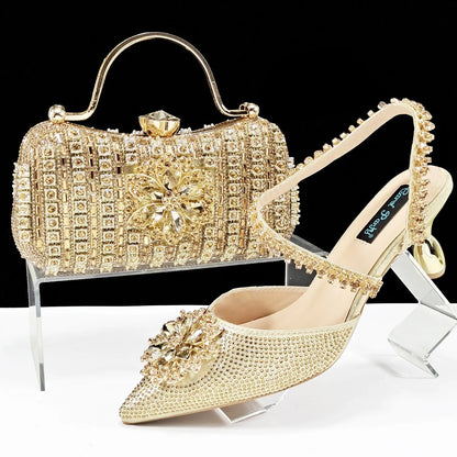 Women's black high-heel ankle strap shoes with floral rhinestone buckle and matching clutch bag on a neutral background