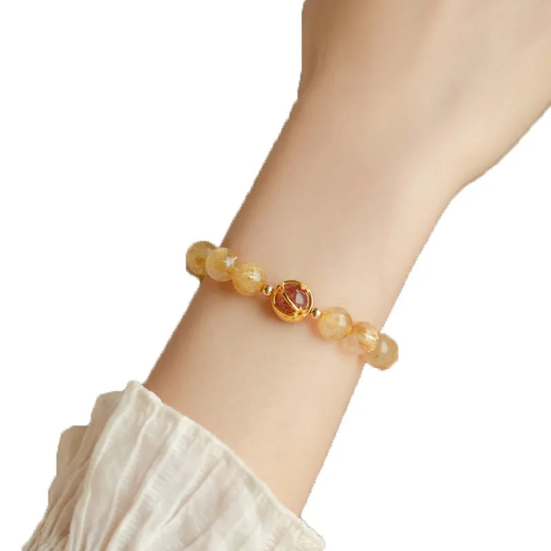 Citrine and gold rutilated quartz stretch bracelet with diamond-cut beads on an elastic band.