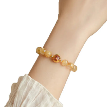 Citrine and gold rutilated quartz stretch bracelet with diamond-cut beads on an elastic band.