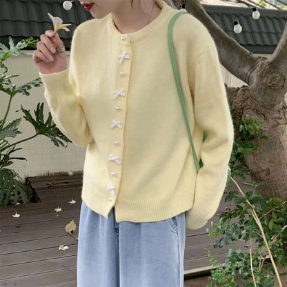 Women's solid colour cardigan sweater with bow pattern and pearl buttons in light blue.