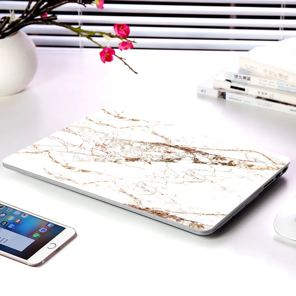 Plastic MacBook protective case in a marble pattern colour, shown next to a compatible Apple laptop.