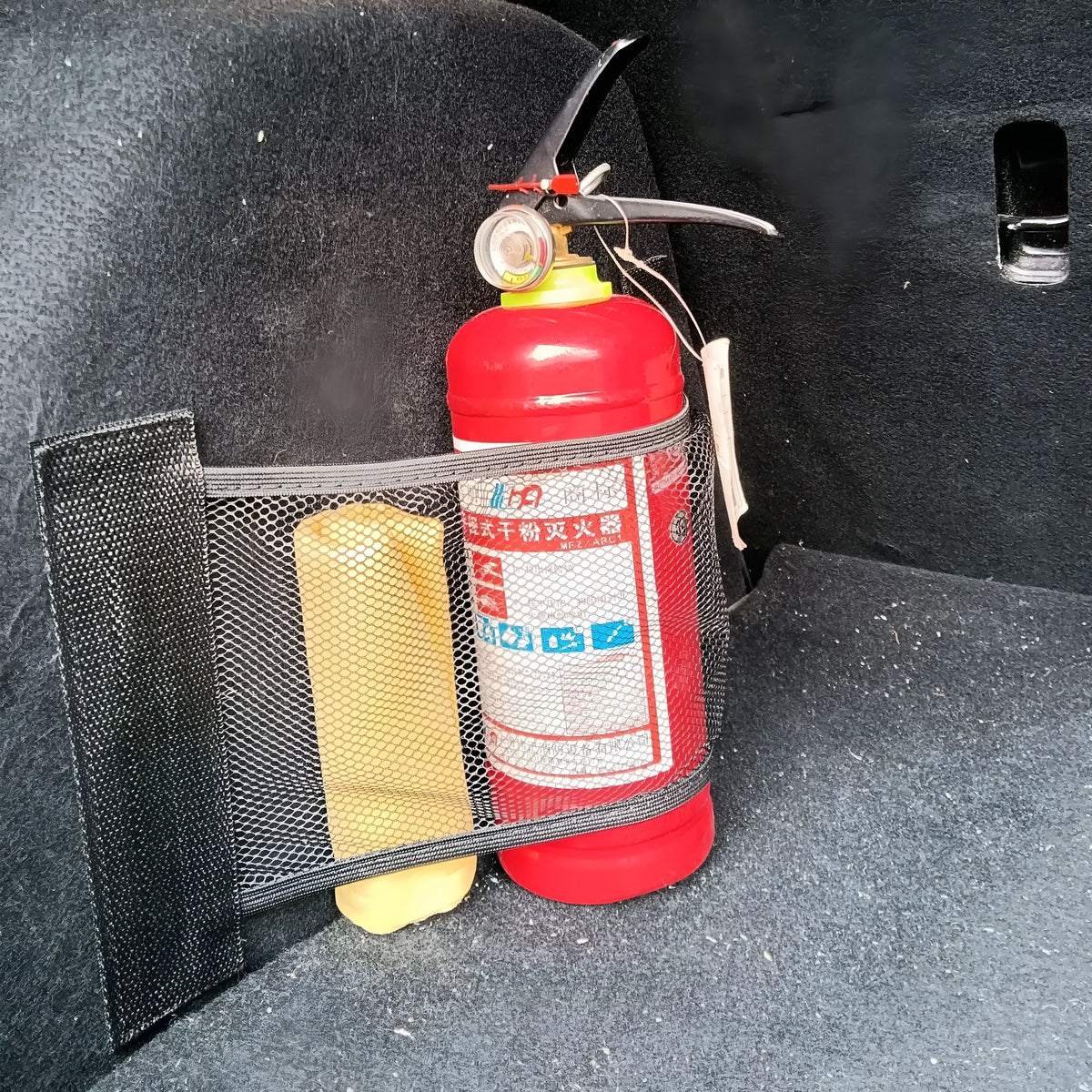A stretchy polyester car boot storage net in a vehicle trunk, holding loose items securely.