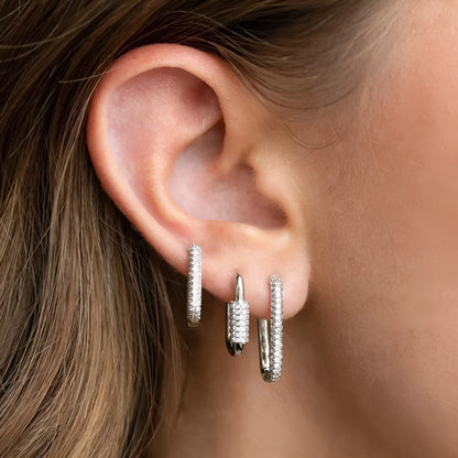 Three geometric copper ear clips with micro inlaid zircon in gold and white tones on a grey background.