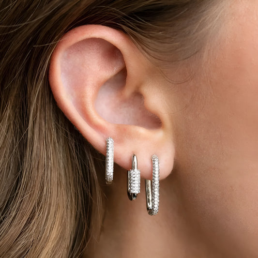 Three geometric copper ear clips with micro inlaid zircon in gold and white tones on a grey background.