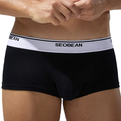 Men's solid colour cotton low waist boxers in white, blue grey, cyan, and black on a size label.