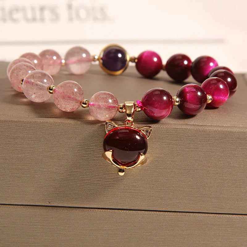 Simple women's bracelet with a red strawberry crystal charm on a black elastic rope.