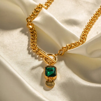 Gold tone geometric pendant necklace with emerald zircon stone on a Cuban link chain.