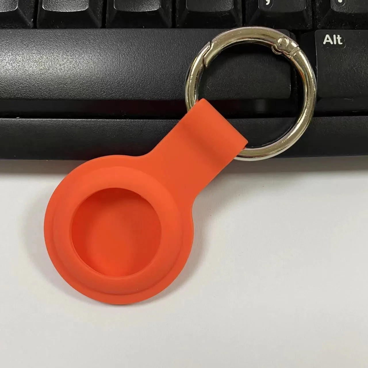 Black waterproof silicone Airtag protective case with metal keychain clip, shown next to colour options.