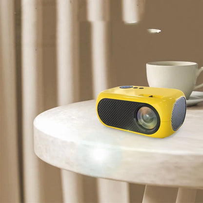 M24 gold and white portable mini LED projector with remote on a wooden table.