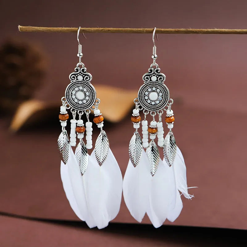 Bohemian feather leaf pattern alloy earrings in round drop shape on a colour selection background.