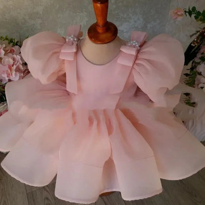 Pink flower girl dress with puffy sleeves and princess bow, shown on mannequin