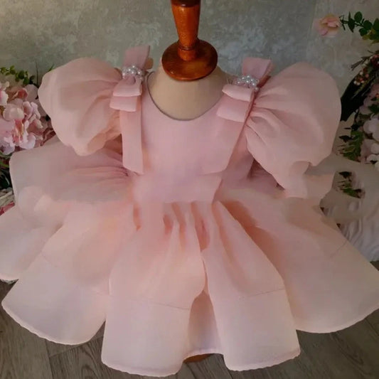 Pink flower girl dress with puffy sleeves and princess bow, shown on mannequin