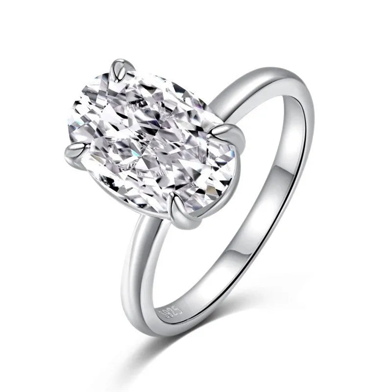 Oval silver ring with four-prong setting and a hand-cut stone on a finger.