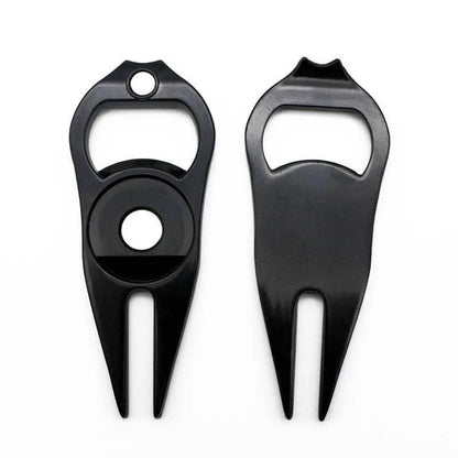 A black zinc alloy golf ball yoke tool with a bottle opener and a separate ball coin on a putting green.
