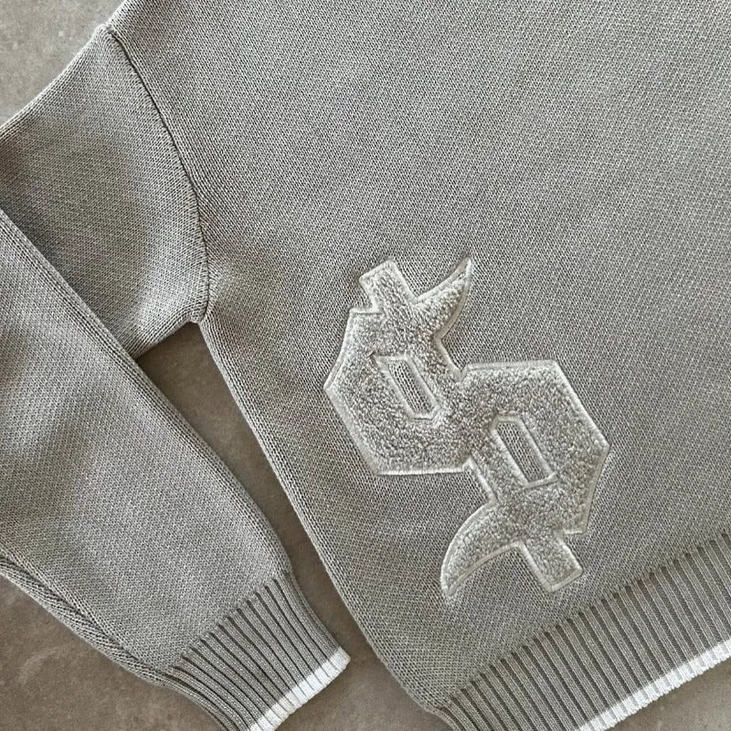 Grey loose-fitting jacquard knit coat with long sleeves on a hanger