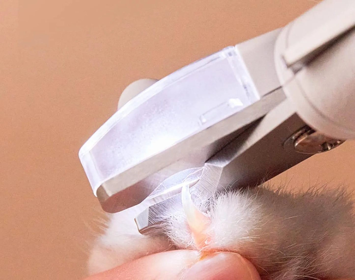 White pet nail clippers with LED light, anti-splash guard, and built-in nail file on a flat surface.