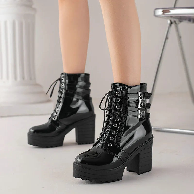 Women's black lace-up ankle boots with a round toe and thick 6-8cm platform heel on a wooden floor.