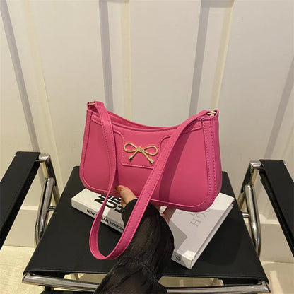 Western style shoulder bag with bow detail in rose pink colour, showing horizontal square shape and single strap.
