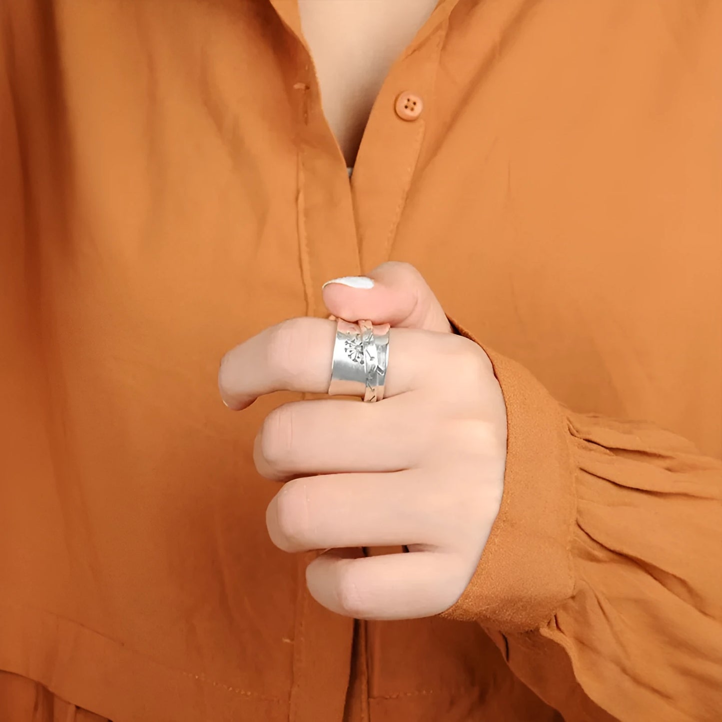 Silver-coloured rotating flower ring on finger showing adjustable floral element