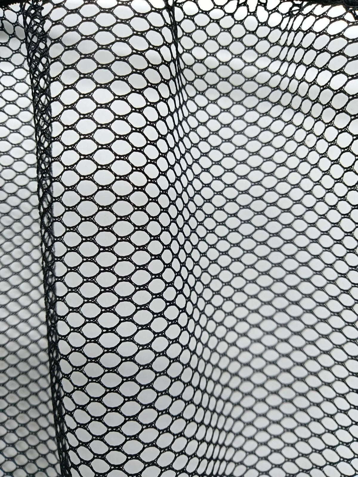 A stretchy polyester car boot storage net in a vehicle trunk, holding loose items securely.