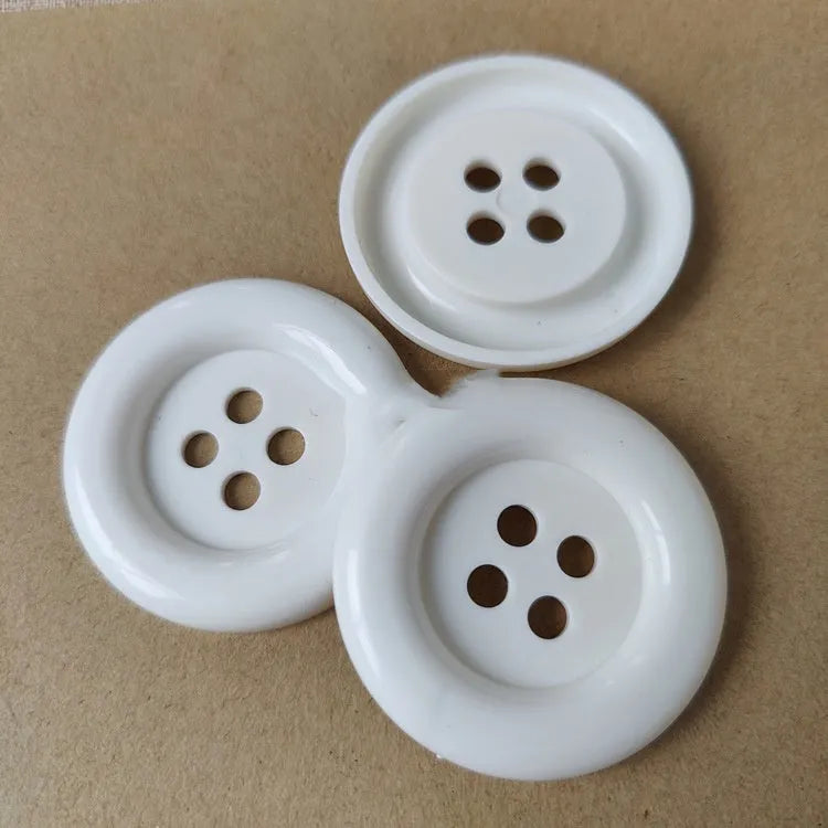 Assorted oversized round plastic buttons in various colours showing four-hole sew-through design.