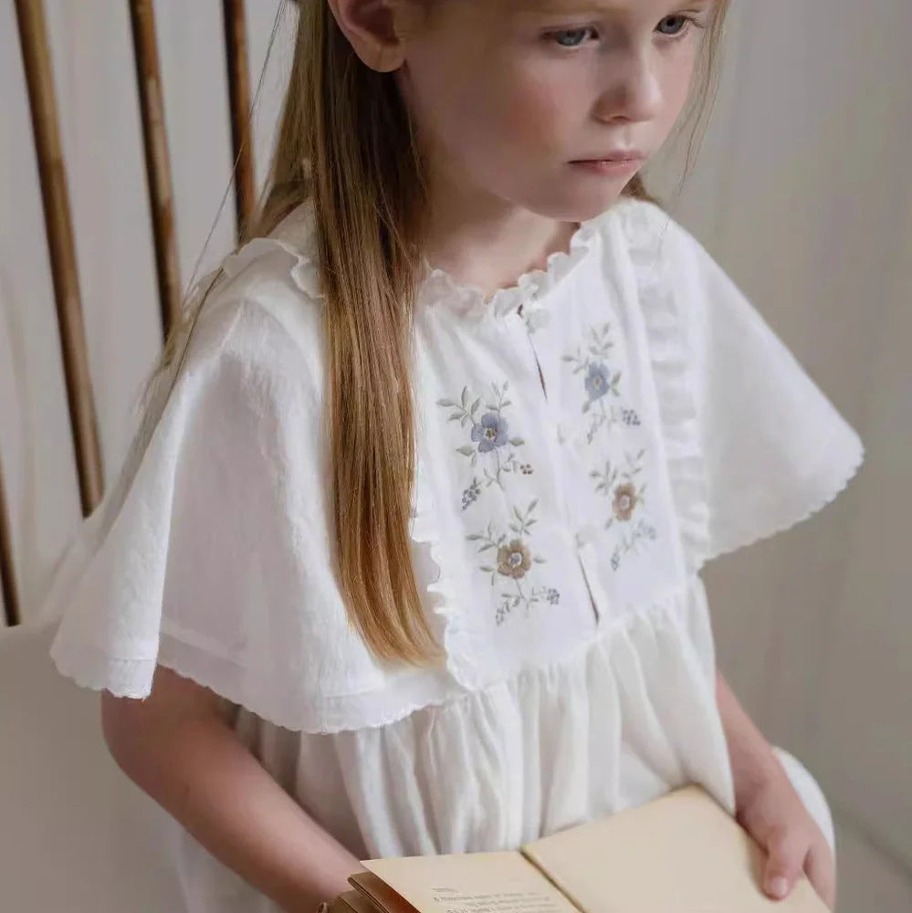 White cotton girls dress with embroidered skirt detail, short sleeves, and Western style silhouette