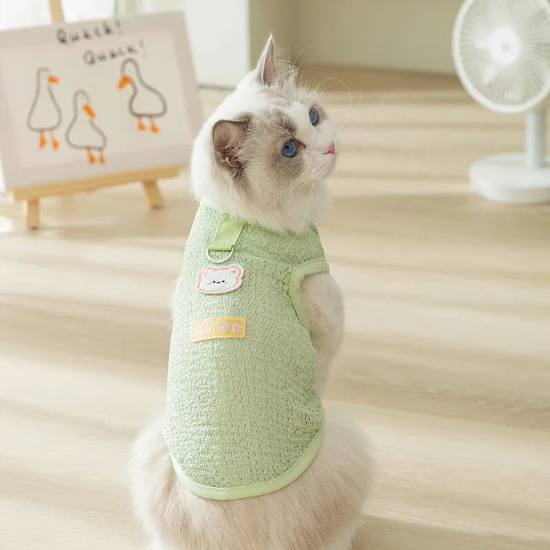 Green knitted cat clothing with a cartoon bear patch, showing hollowed-out breathable design.