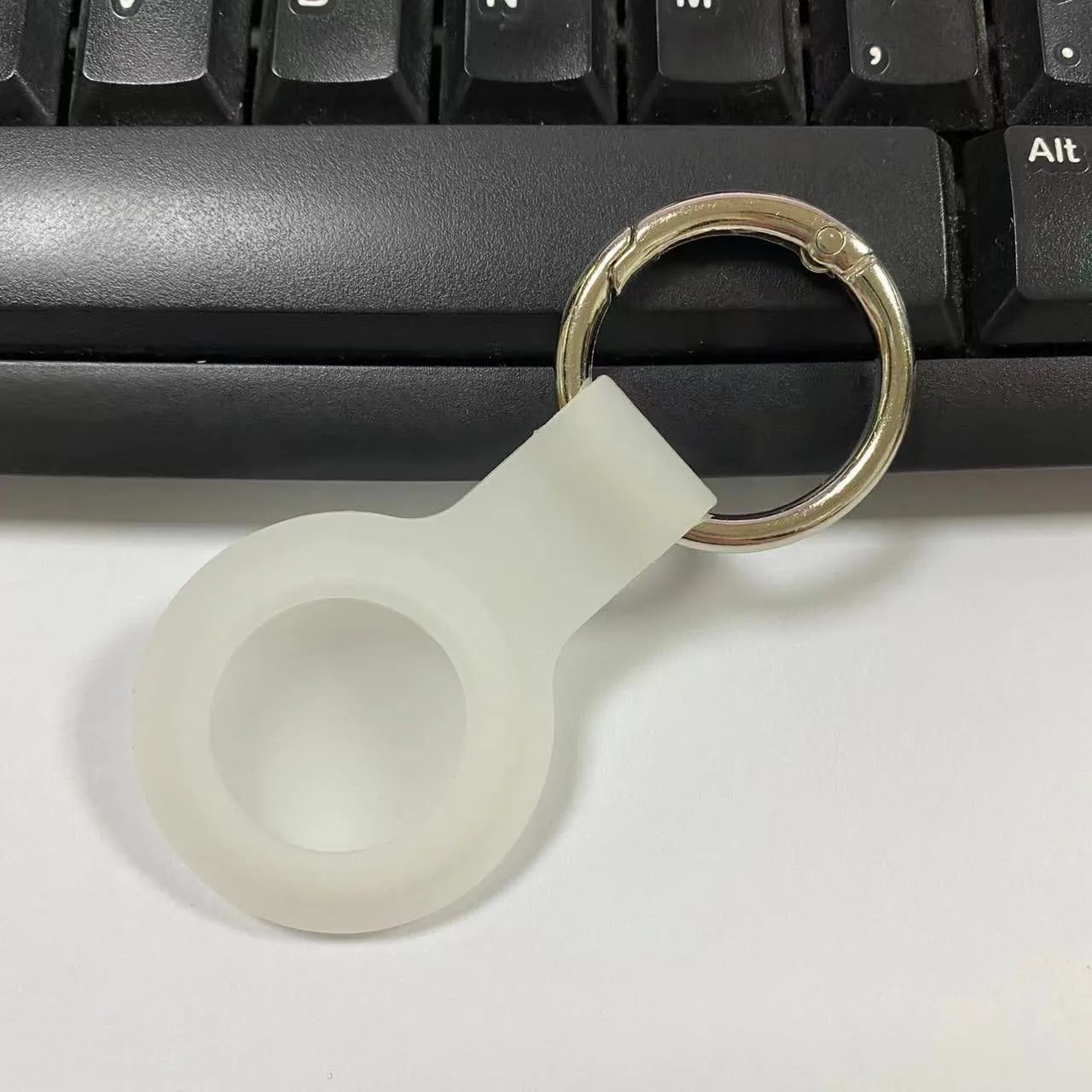 Black waterproof silicone Airtag protective case with metal keychain clip, shown next to colour options.