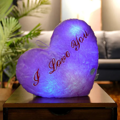 Colourful glowing five-pointed star plush pillow on a dark background.