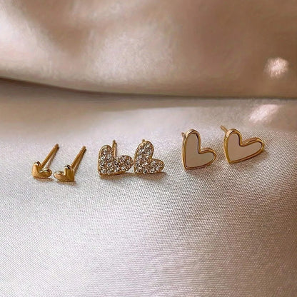 Three pairs of heart-shaped electroplated earrings in gold, black, black and white, and pink colours