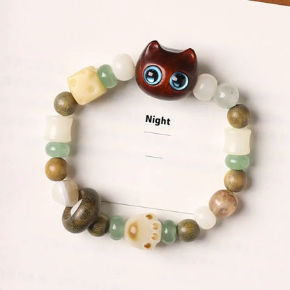 Hand-woven multi-treasure bracelet with jade, bodhi and ebony wood beads and a cartoon cat's paw charm.