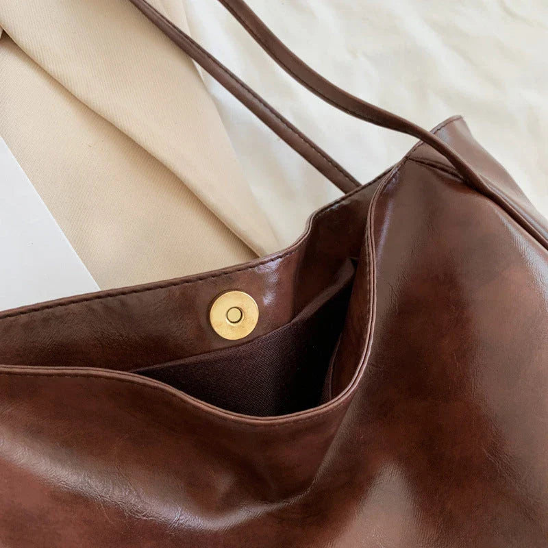 Stylish leather shoulder bag in various colors, including wine red, blue, black, brown, and beige. Showcases a versatile and spacious design for everyday use.