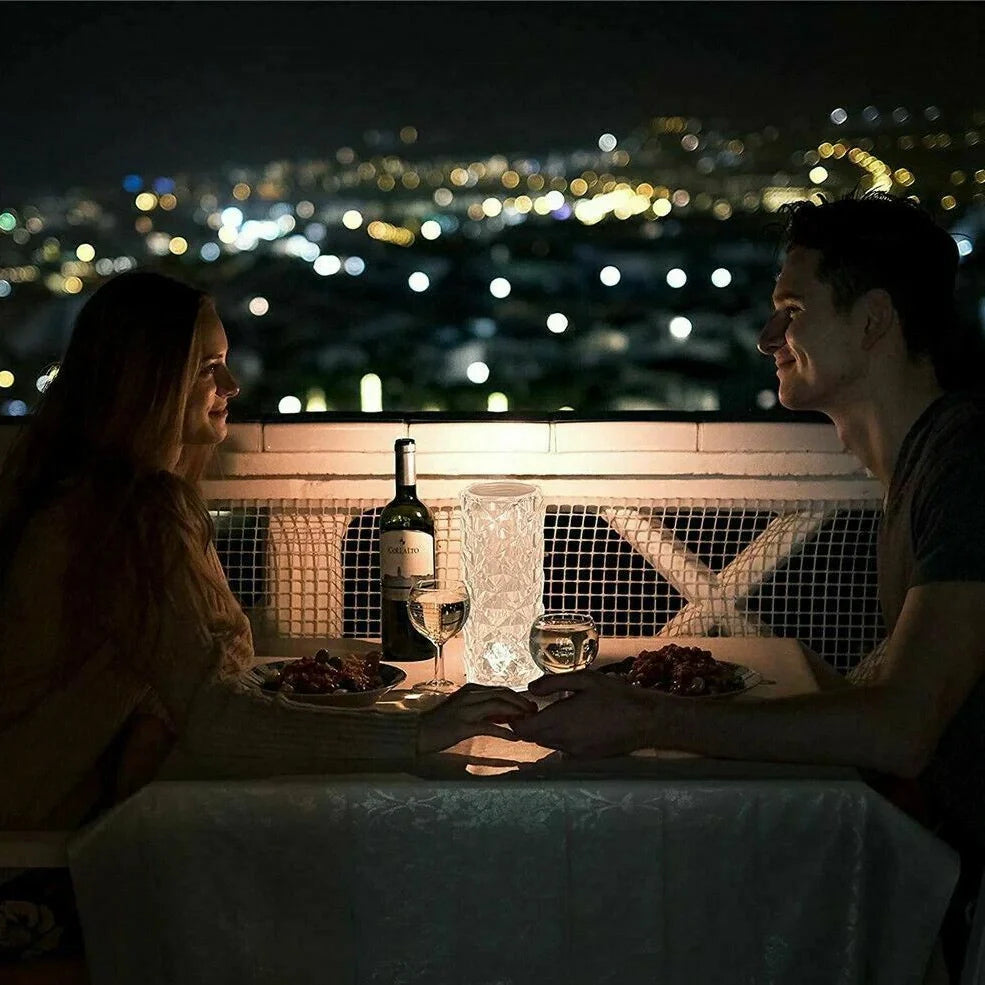 Clear acrylic LED table lamp with diamond-cut surfaces and remote control on wooden surface