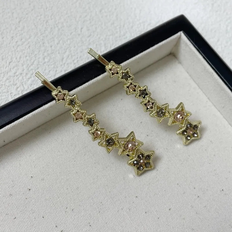 Gold electroplated hair barrette with a rhinestone five-pointed star, broken clip style for bangs.