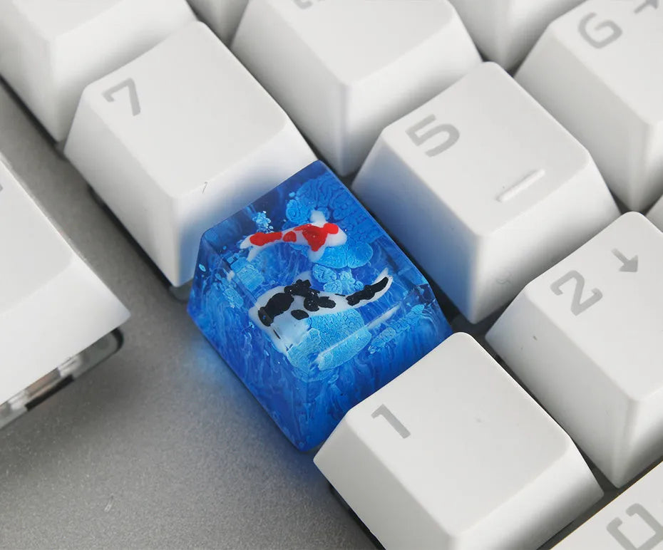 Close-up of a custom resin keycap featuring a detailed blue and orange koi fish scene, designed for Cherry MX mechanical keyboards.
