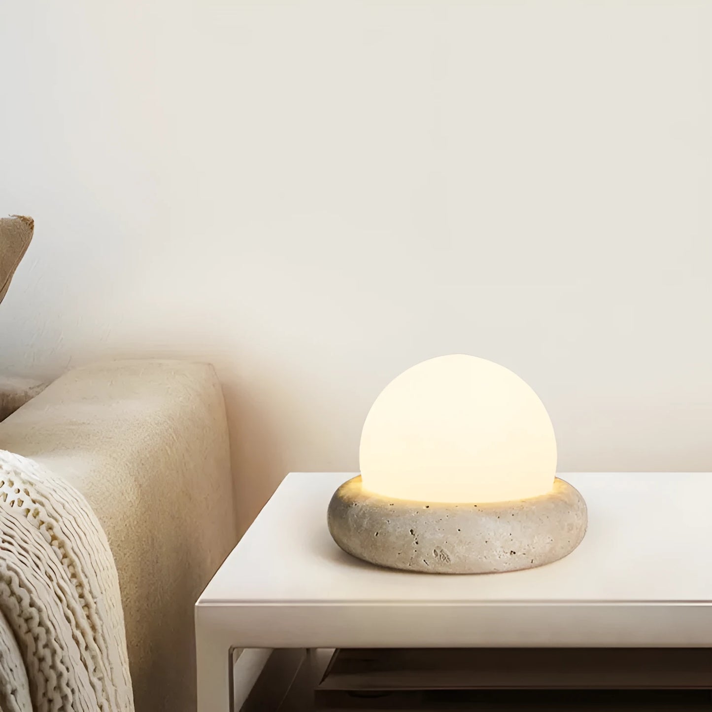 Modern white bedside night lamp with remote control on a wooden table.