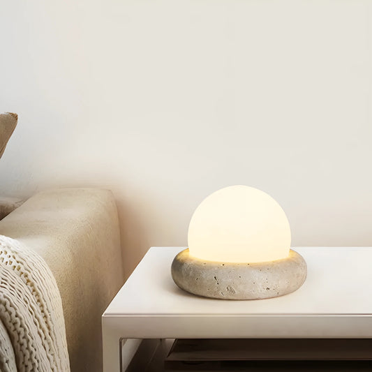Modern white bedside night lamp with remote control on a wooden table.