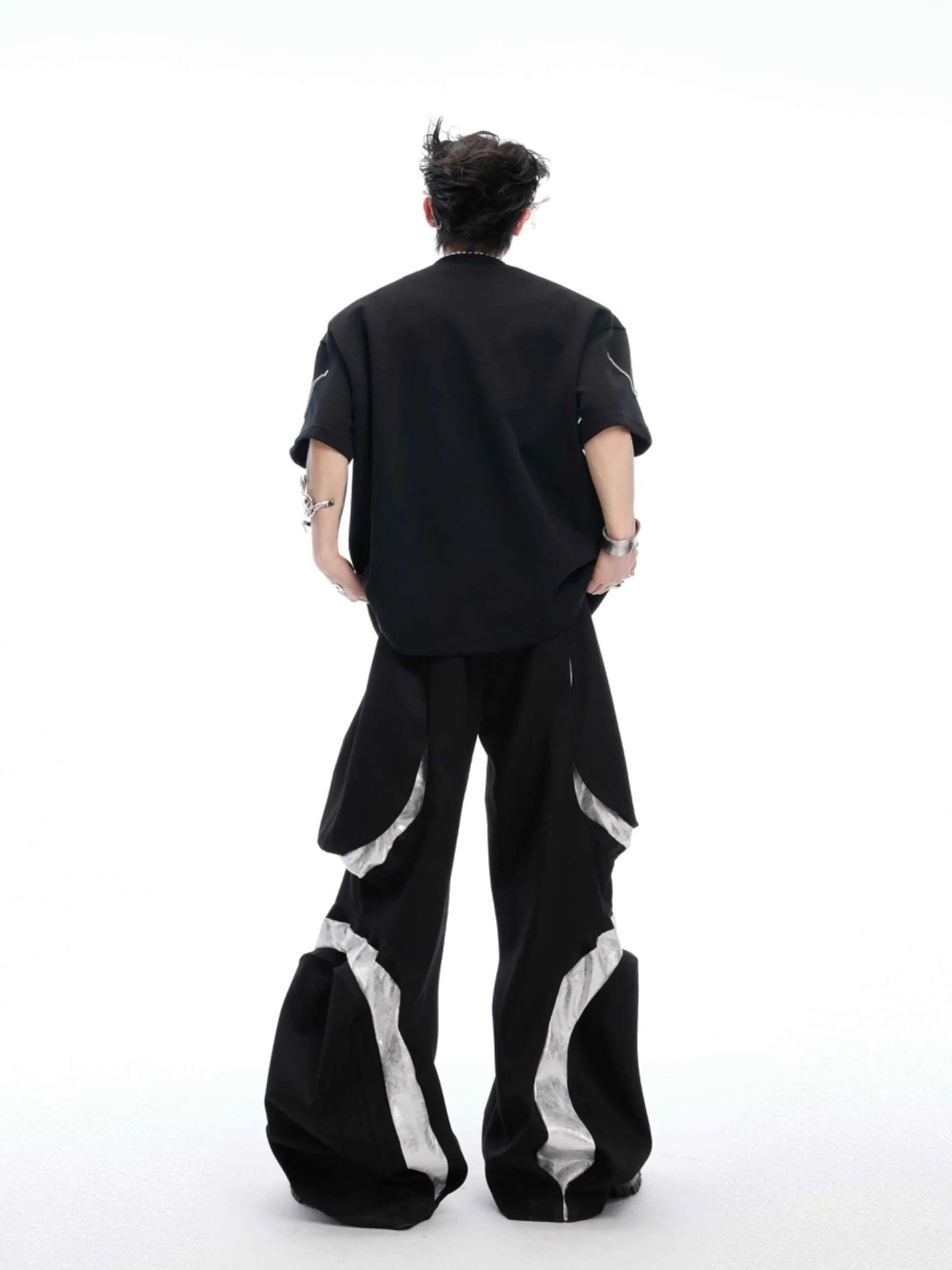 Black padded shoulder T-shirt with metal chain detail on model, showing short sleeves and round neck.