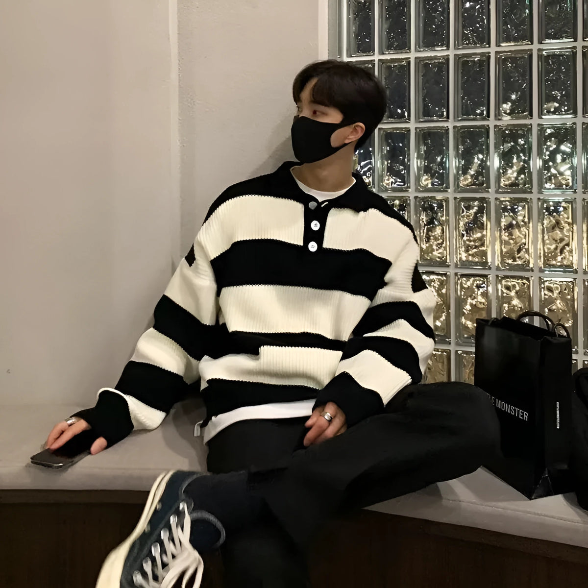 Man wearing a loose-fit black and grey striped polyester pullover sweater
