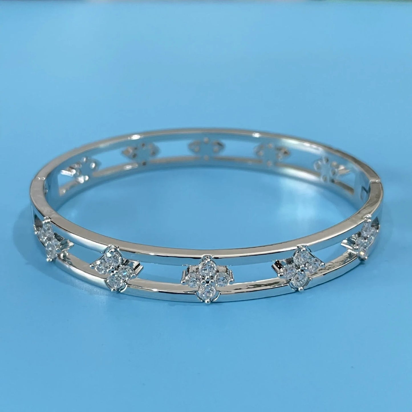 Hollow women's bracelet with four-leaf clover design and inlaid zircon stones in gold or silver finish.