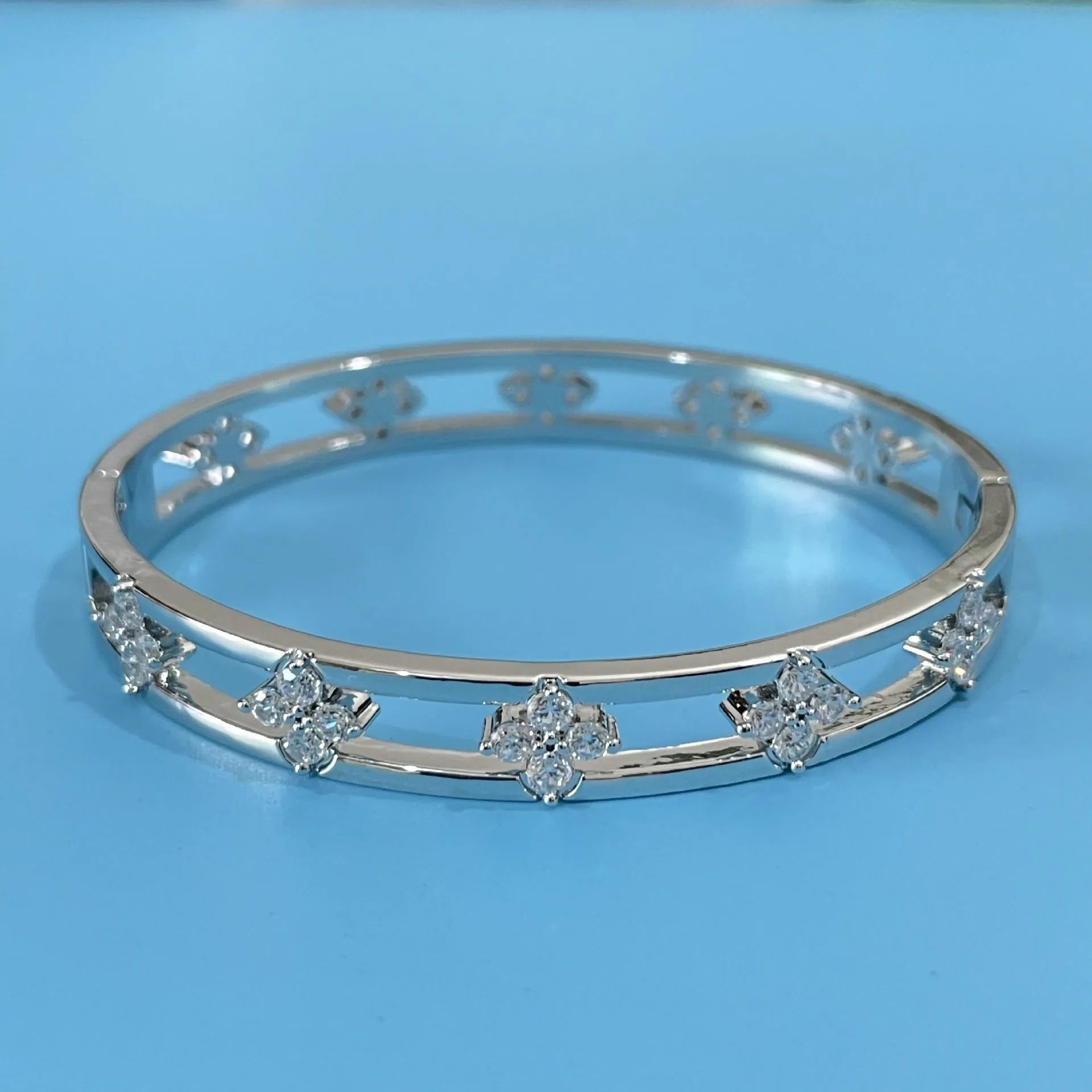 Hollow women's bracelet with four-leaf clover design and inlaid zircon stones in gold or silver finish.